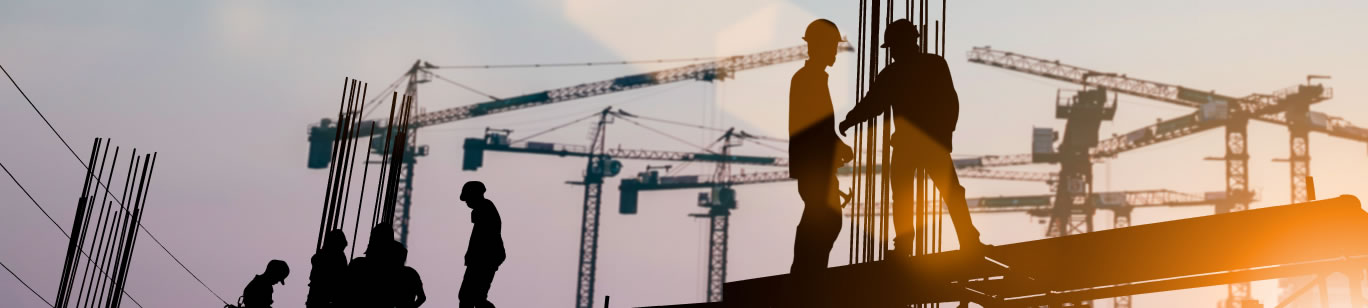 Silhouetted construction workers on steal beams
